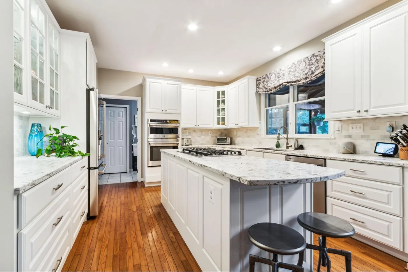 Sold home — bright white kitchen with marble island and hardwood floors