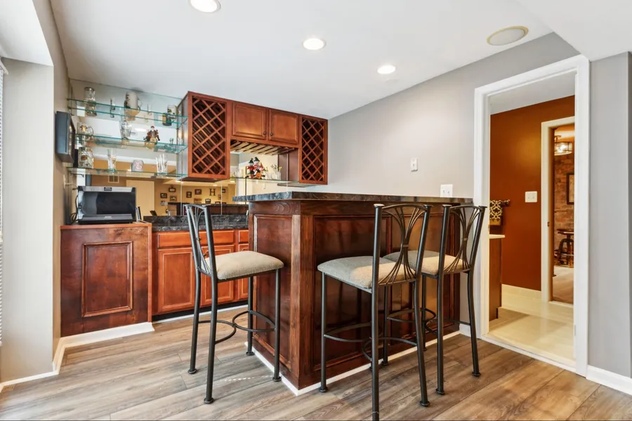 Sold home — lower-level wet bar with cherry cabinetry and bistro chairs